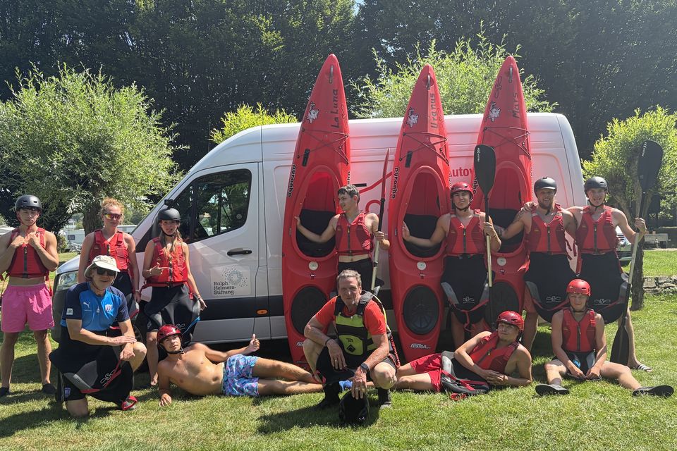 Die Kajak-Gruppe mit ihren Booten und Sicherheitsausrüstung auf der Wiese
