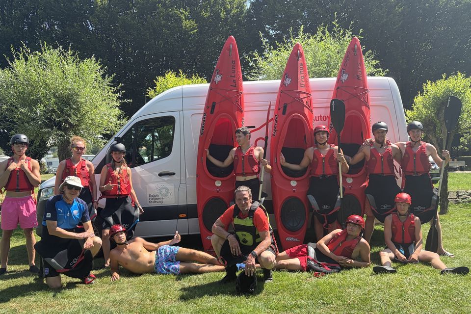 Die Kajak-Gruppe mit ihren Booten und Sicherheitsausrüstung auf der Wiese